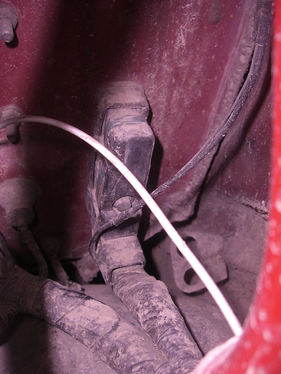 Dusty wiring harnesses and a black electrical component in a vehicle.