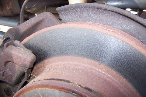 1990 Ford Bronco - A close-up view of a heavily rusted brake rotor and caliper assembly, likely from a 1990 Ford Bronco. The brake rotor shows significant wea…