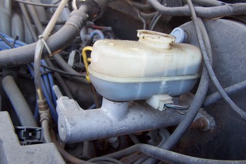 1990 Ford Bronco - Close-up of a Ford brake master cylinder and fluid reservoir, showing various hoses and wiring.