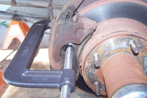 1990 Ford Bronco - Brake caliper and rotor assembly being worked on with a C-clamp.