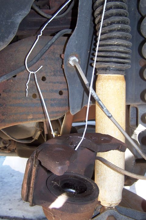 1990 Ford Bronco - Close-up of a damaged vehicle suspension component, showing rust and a broken ball joint.