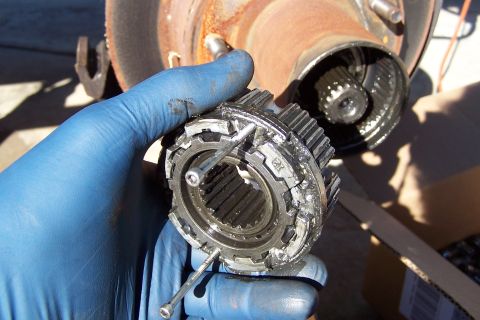 1990 Ford Bronco - A damaged manual locking hub part is held by a gloved hand, with the vehicle's hub assembly visible in the background.