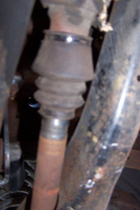 1990 Ford Bronco - Close-up view of a vehicle's driveshaft boot and U-joint, showing signs of rust and wear.
