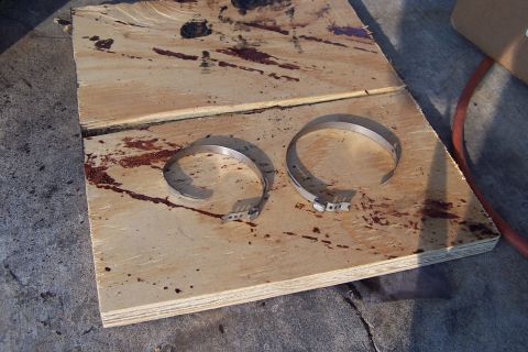 1990 Ford Bronco - Two CV axle boot clamps are shown on a stained wooden board, possibly removed from a vehicle.
