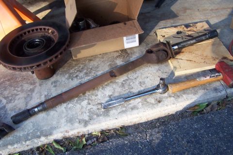 1990 Ford Bronco - Driveshaft and brake rotor laid out on concrete with tools.