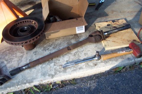 1990 Ford Bronco - Various automotive parts and tools are spread out on a concrete surface, suggesting a repair or maintenance activity.