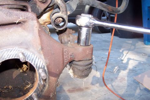 1990 Ford Bronco - Close-up of a worn ball joint being worked on, with a socket wrench in place.
