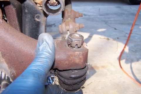 1990 Ford Bronco - Close-up view of a vehicle's ball joint, showing the cotter pin nut and protective rubber boot.