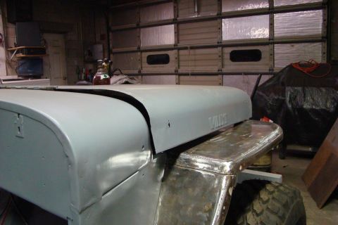 1948 Jeep Wrangler - A 1948 Jeep Wrangler undergoes bodywork in a garage setting, with the hood and fender prominently displayed.