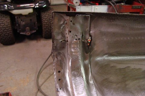 1948 Jeep Wrangler - This image shows a damaged metal panel undergoing repair, with evidence of rust and recent welding work.