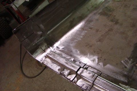 1948 Jeep Wrangler - Close-up of a metal panel undergoing body work, showing welds and grinding marks.