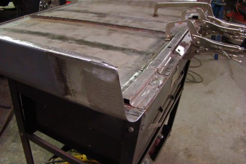 1948 Jeep Wrangler - Metal panel held by clamps, likely in a workshop setting for repair or fabrication.