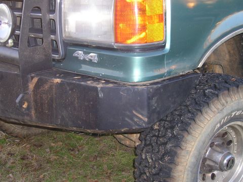1989 Ford Bronco - Close-up of a green SUV's front corner, a "4x4" badge and a bumper.