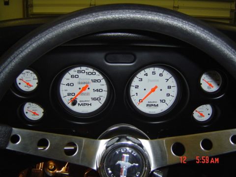 1970 Ford Mustang - Close-up of a car's dashboard, showing various gauges and a Ford Mustang steering wheel emblem.