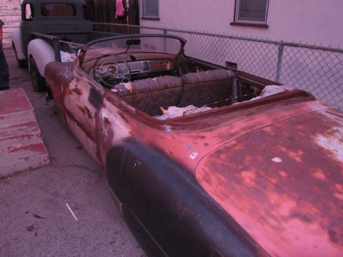 1986 Ford Bronco - A weathered convertible sits beside a pickup truck, its interior showing signs of age and disrepair.