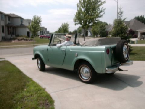 1993 Ford Bronco - This light green convertible SUV is parked on a driveway with houses in the background.