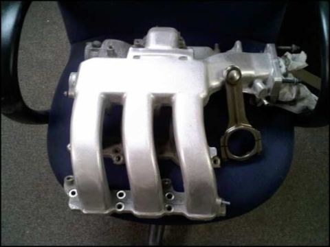 1994 Ford Probe - An engine intake manifold and connecting rod are displayed on a chair.