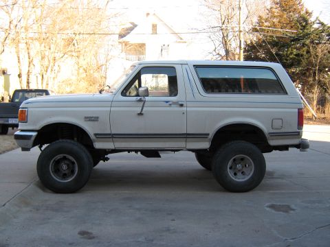 1987 Ford Bronco - This 1987 Ford Bronco is shown from the side, a lifted suspension and aftermarket wheels.