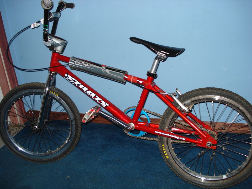 Red BMX bike with 'STAATS' and 'Roy Lee Designs' graphics, and Maxxis tires