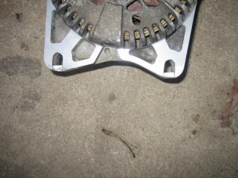 1996 Ford Thunderbird - This photo shows a close-up view of an automotive alternator part resting on a concrete floor.
