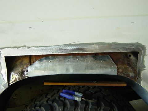 1993 Ford Bronco - Repair work is underway on the wheel well of a white vehicle.