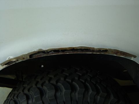 1993 Ford Bronco - Close-up view of significant rust damage around a vehicle's wheel well.