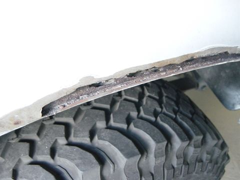 1993 Ford Bronco - Close-up of a 1993 Ford Bronco's rusted wheel well edge, with a tire visible below.
