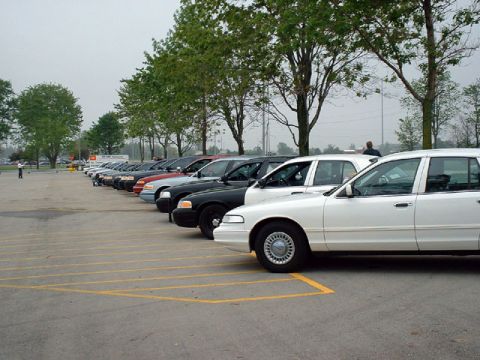 2000 Ford Crown Victoria - Multiple Ford Crown Victoria police cars are parked in a lot, with a white one in the foreground.