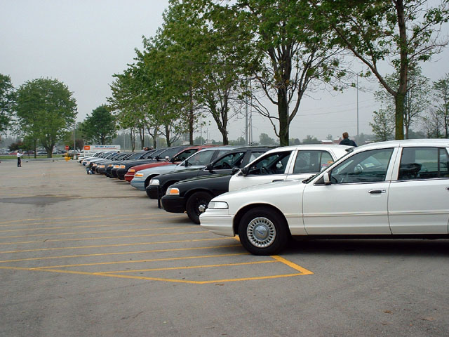 Line of white and black Ford Crown Victoria police cars parked in a lot