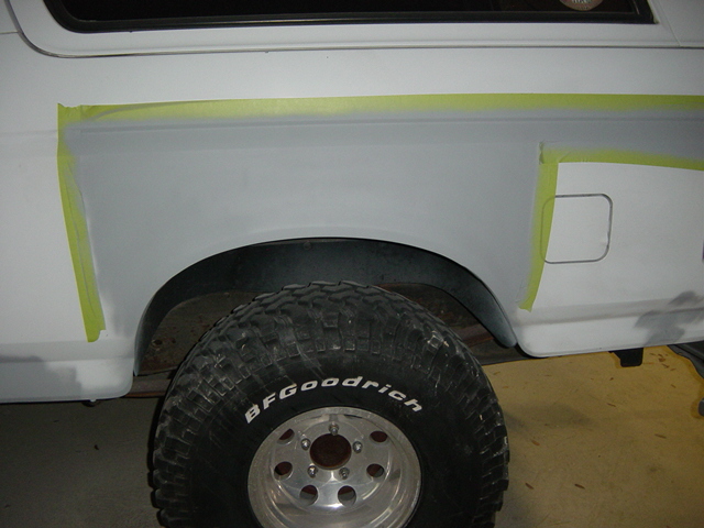 White Ford Bronco rear quarter panel masked off for bodywork, showing a large BFGoodrich tire