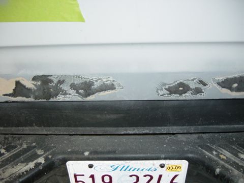 1993 Ford Bronco - Body filler applied to a vehicle's rear panel during repair work.
