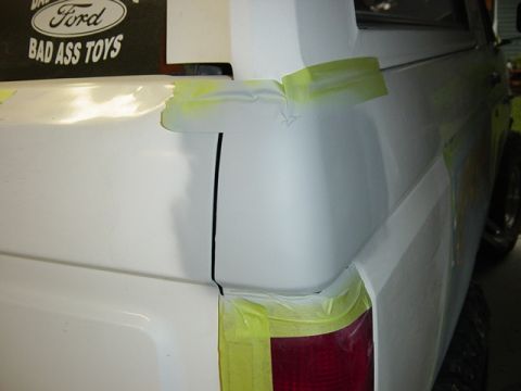 1993 Ford Bronco - A white 1993 Ford Bronco's rear quarter panel is prepped for paint with masking tape.
