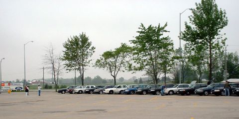 2000 Ford Crown Victoria - A row of police cruisers are parked in an outdoor lot on an overcast day.