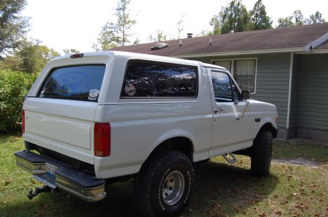 1993 Ford Bronco - Rear view of a white 1993 Ford Bronco parked in a residential yard.