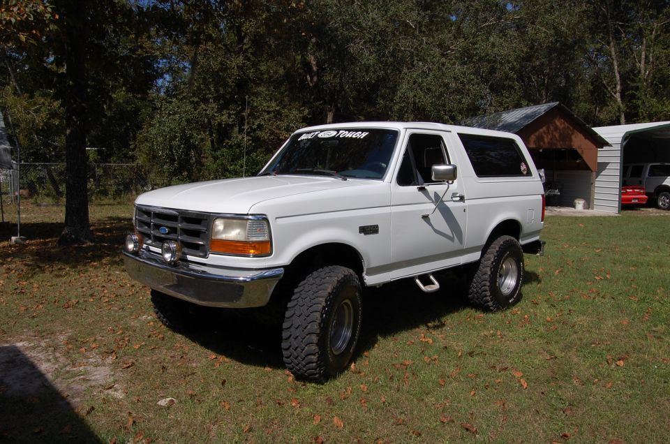 White 1993 Ford Bronco with aftermarket wheels and lights