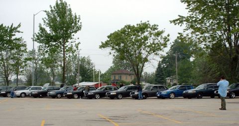 2000 Ford Crown Victoria - Multiple sedans are parked in an outdoor lot under an overcast sky.