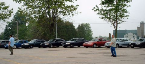 2000 Ford Crown Victoria - Several Ford Crown Victorias are parked in a lot, with a man walking in the foreground.