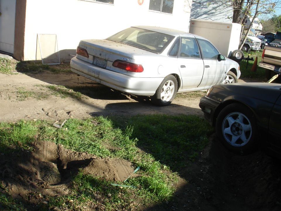 Silver four-door sedan parked on dirt lot.