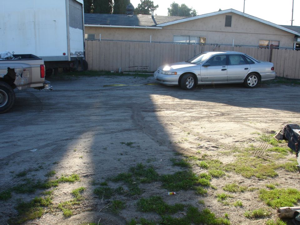 Silver sedan parked on a dirt lot with a white box truck.