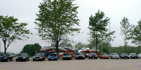 2000 Ford Crown Victoria - A lineup of police cars and other sedans are parked in a lot, with trees in the background.