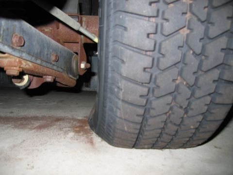 1991 Ford LTD Crown Victoria - Photograph of a vehicle rear tire and leaf-spring suspension from below, not a technical document.