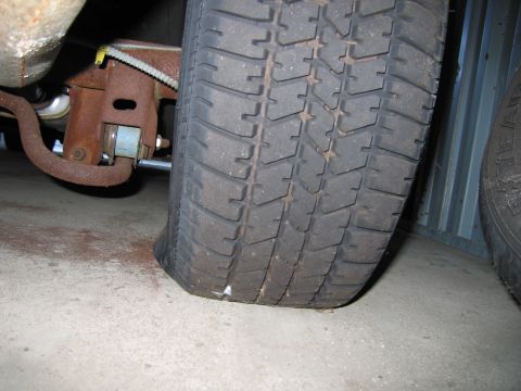 1991 Ford LTD Crown Victoria - Photograph of a tire and rear suspension components under a vehicle, not a technical document.