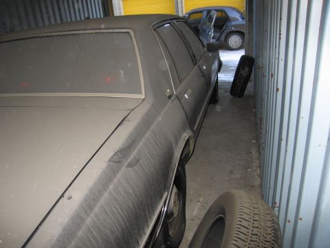 1991 Ford LTD Crown Victoria - Photograph of a dust-covered sedan parked in a storage container, not a technical document.