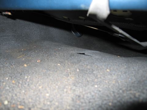 1991 Ford LTD Crown Victoria - Photograph of vehicle interior floor carpet under a seat, not a technical document.