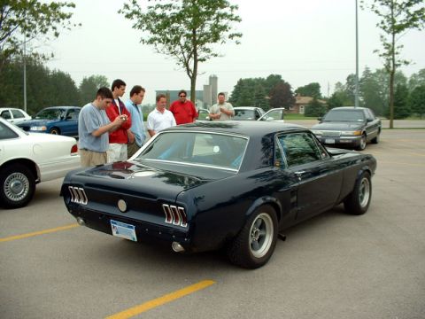 2000 Ford Crown Victoria - A dark blue coupe is parked in a lot with several people standing nearby.