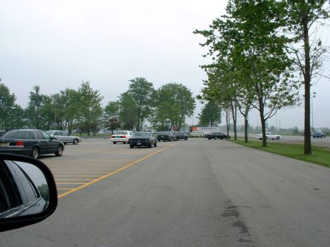 2000 Ford Crown Victoria - A dark 2000 Ford Crown Victoria is parked in a lot alongside other vehicles on a cloudy day.