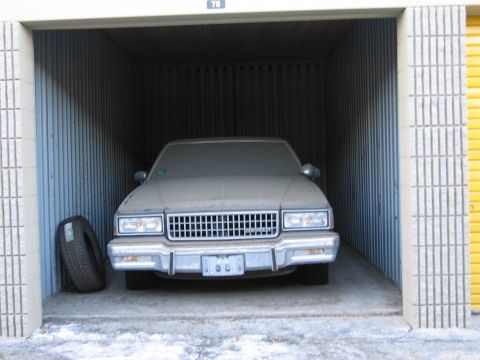 1991 Ford LTD Crown Victoria - Photo of a stored sedan and spare tire, not a document.