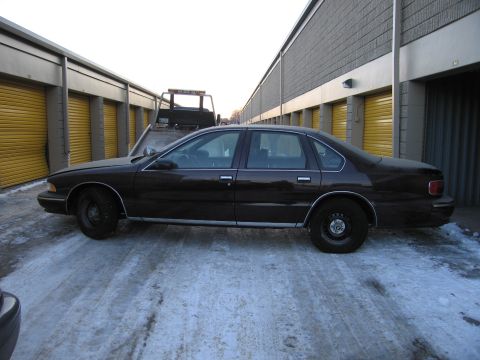 1991 Ford LTD Crown Victoria - Exterior photo of a sedan beside storage units, not a document.