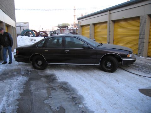 1991 Ford LTD Crown Victoria - Driver-side profile photo of a dark Chevrolet Caprice sedan parked in a snowy storage lot.