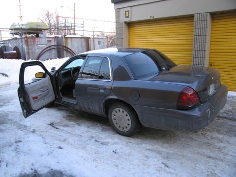 1991 Ford LTD Crown Victoria - Rear three-quarter photo of a gray Ford Crown Victoria sedan with a front door open in a snowy storage lot.
